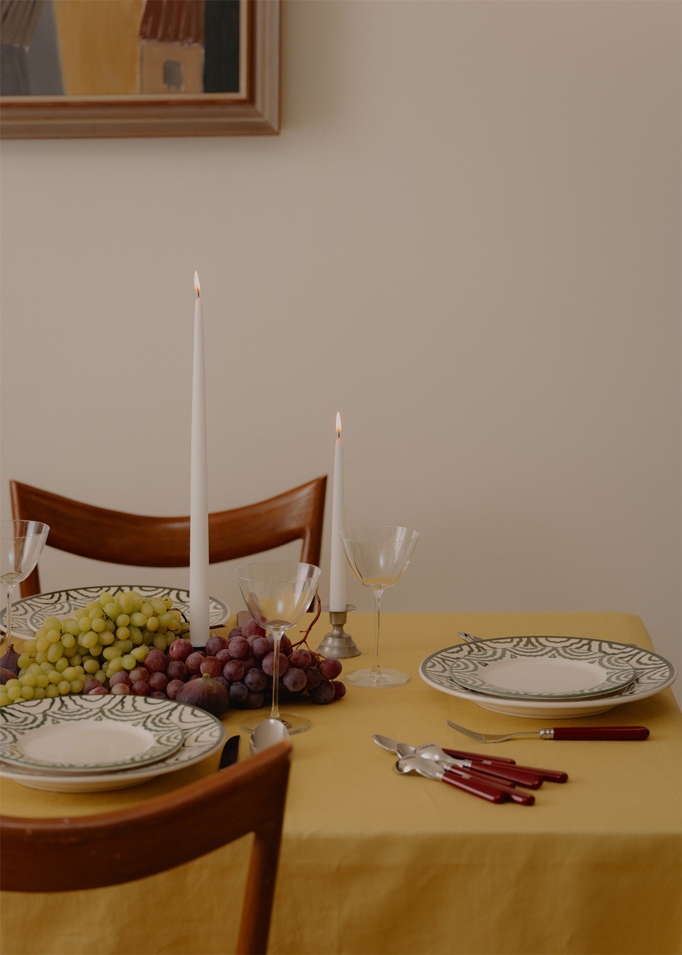 Dining table set with plates, glasses, and cutlery on a yellow tablecloth.