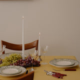 Dining table set with plates, glasses, and cutlery on a yellow tablecloth.