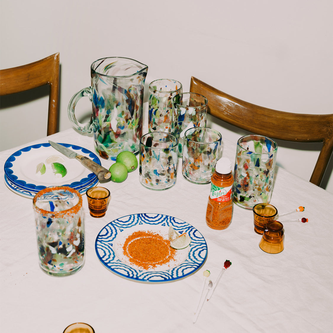 Dining table with glassware, plates, and bottles on a white tablecloth.