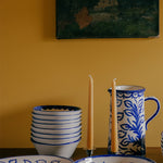 Ceramic tableware with blue and white patterns on a yellow wall background