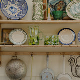 Shelves with decorative plates, mugs, and pots in a kitchen setting.