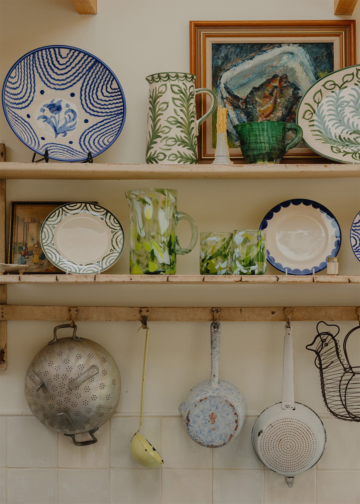 Shelves with decorative plates, mugs, and pots in a kitchen setting.