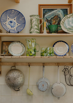Shelves with decorative plates, mugs, and pots in a kitchen setting.