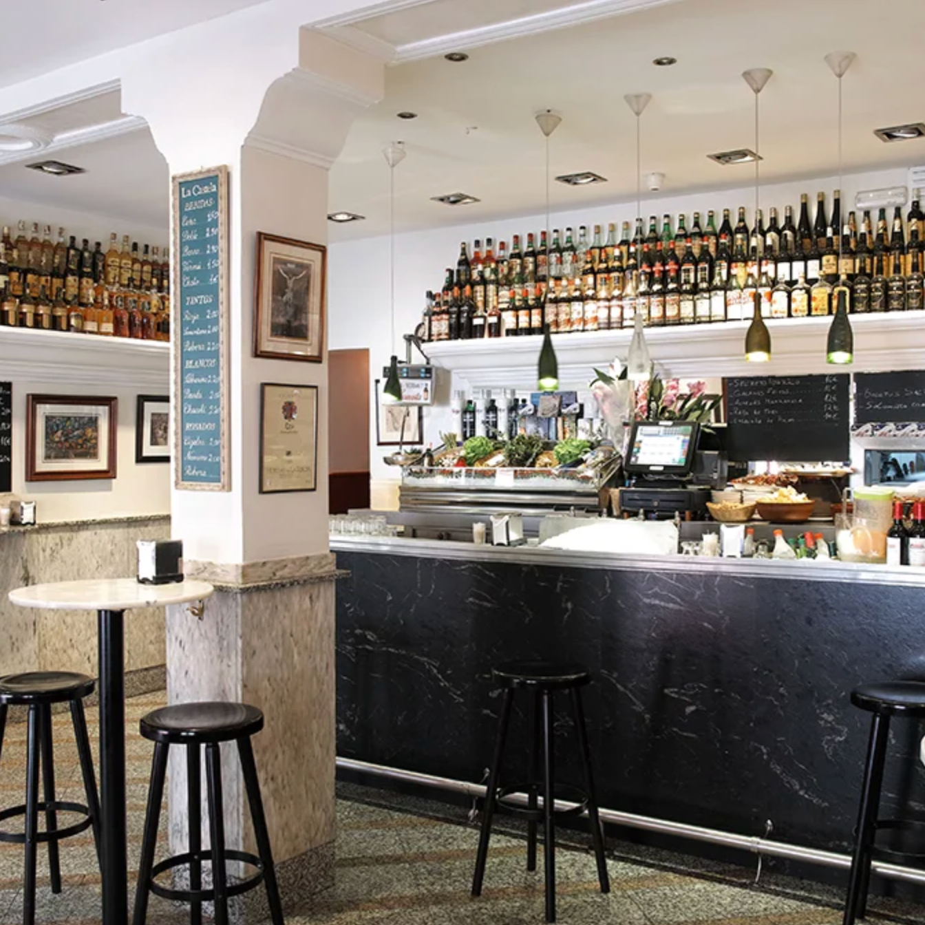 Bar interior with bottles on shelves and stools in front