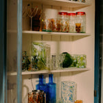 Shelves with various glassware including bottles, cups, and jars.