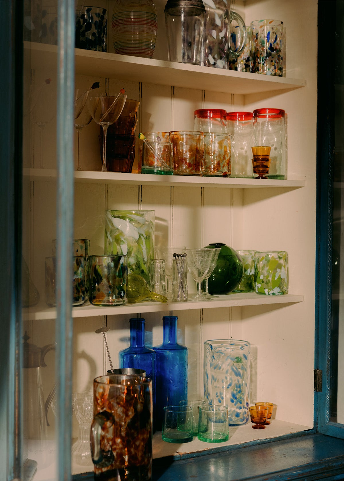 Shelves with various glassware including bottles, cups, and jars.