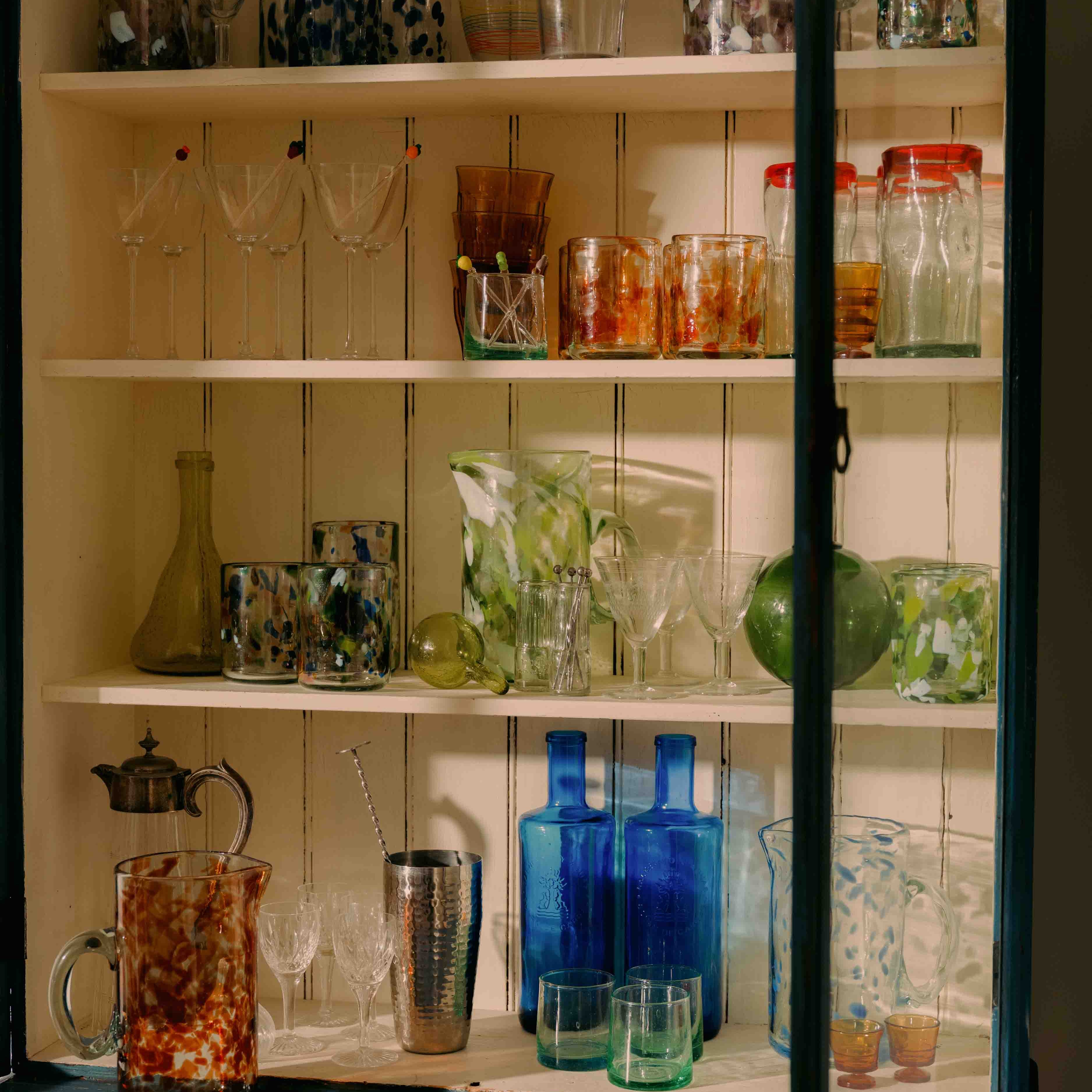 Shelving unit with various glassware including cups, bottles, and glasses.
