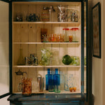 Vintage-style cabinet with glassware and decorative items in a home setting