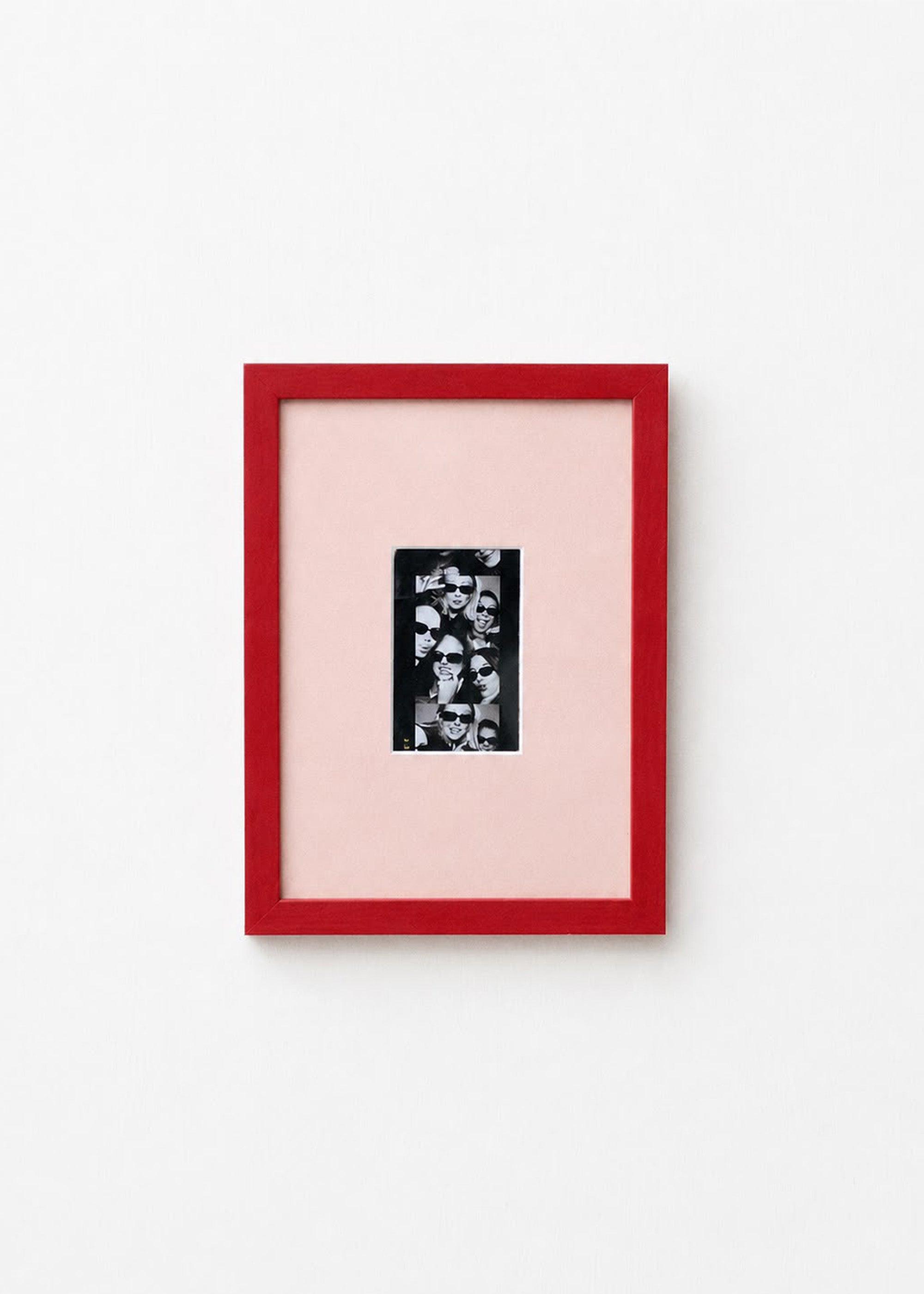 A framed art print featuring a black and white floral pattern on a light pink mat, enclosed in a vibrant red frame against a clean white background.