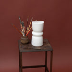 White ceramic decorative wall sconce on a wooden table with a brown background