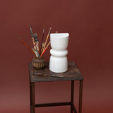 White ceramic decorative wall sconce on a wooden table with a brown background