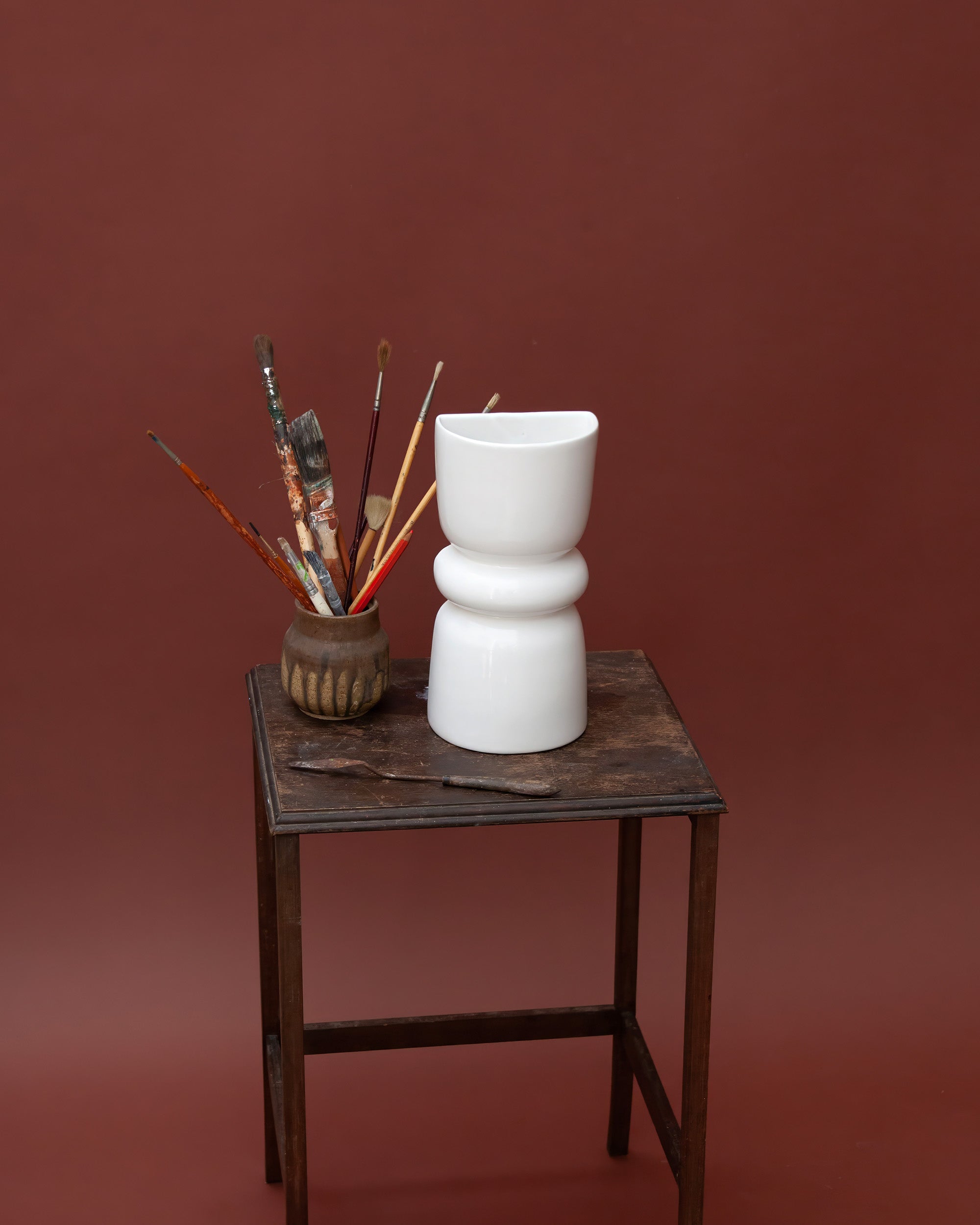 White ceramic decorative wall sconce on a wooden table with a brown background
