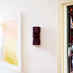 Late Afternoon Lighting Burgundy Up and Down lighter Ceramic Wall Sconce on a white wall with a piece of art.