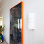 Late Afternoon Lighting White Up and Down lighter Ceramic Wall Light on a white wall next to a photograph in a red frame