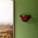 Late Afternoon Lighting Burgundy Uplighter Ceramic Wall Light on a green wall