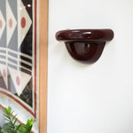 Late Afternoon Lighting Burgundy Uplighter Ceramic Sconce Wall Light hung on a white wall next to a framed print