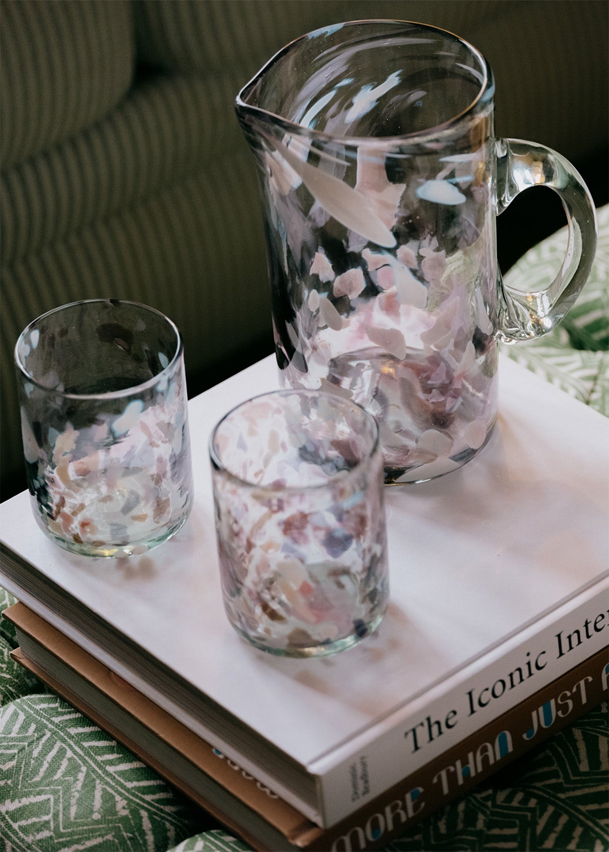 Clear glass pitcher and tumblers with floral design on a book