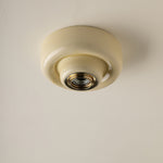 A vintage-style butter yellow-coloured ceiling light fixture with a circular ceramic shade and a brass screw base, shown mounted on a textured off-white ceiling.