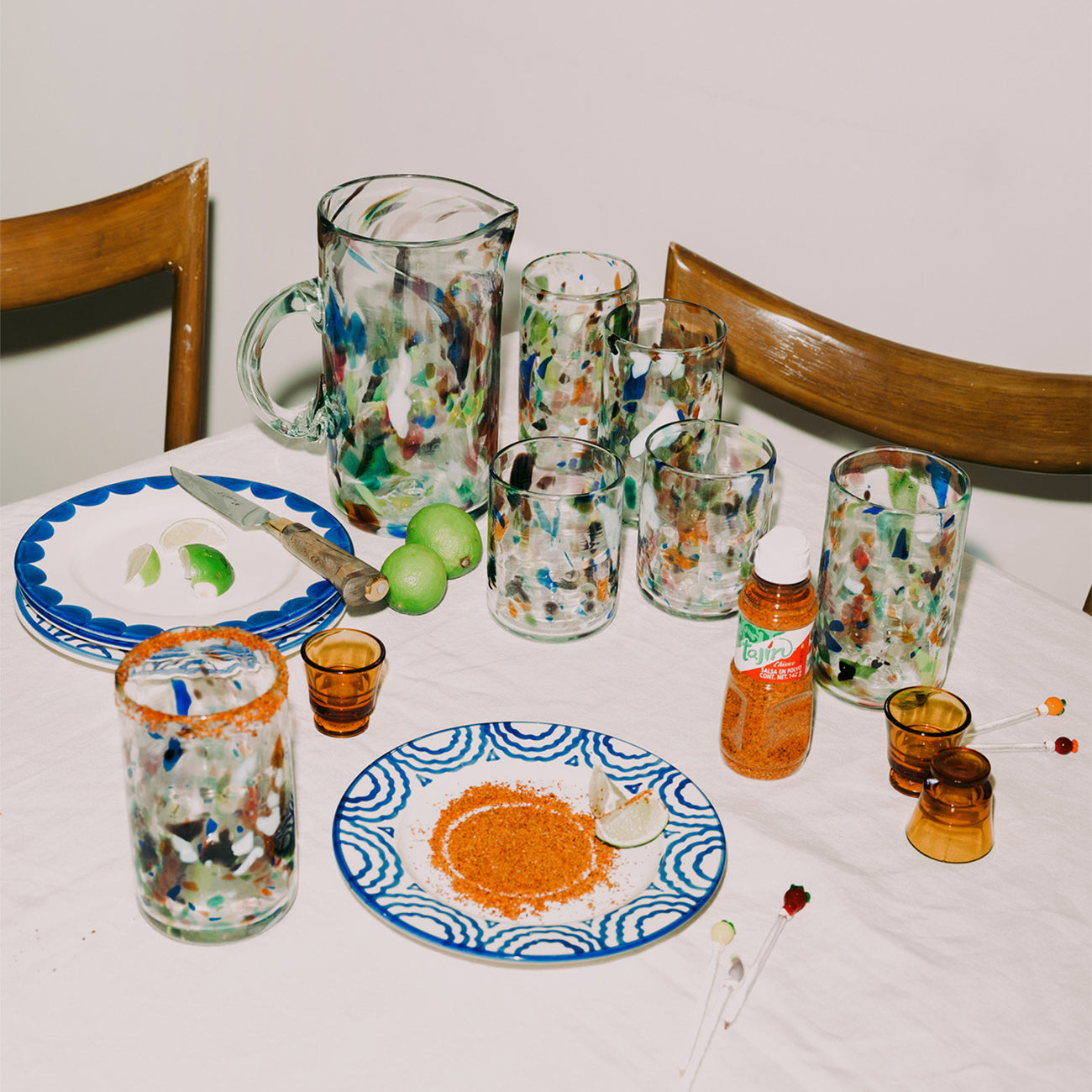 Table setting with colorful glassware and plates on a white tablecloth.