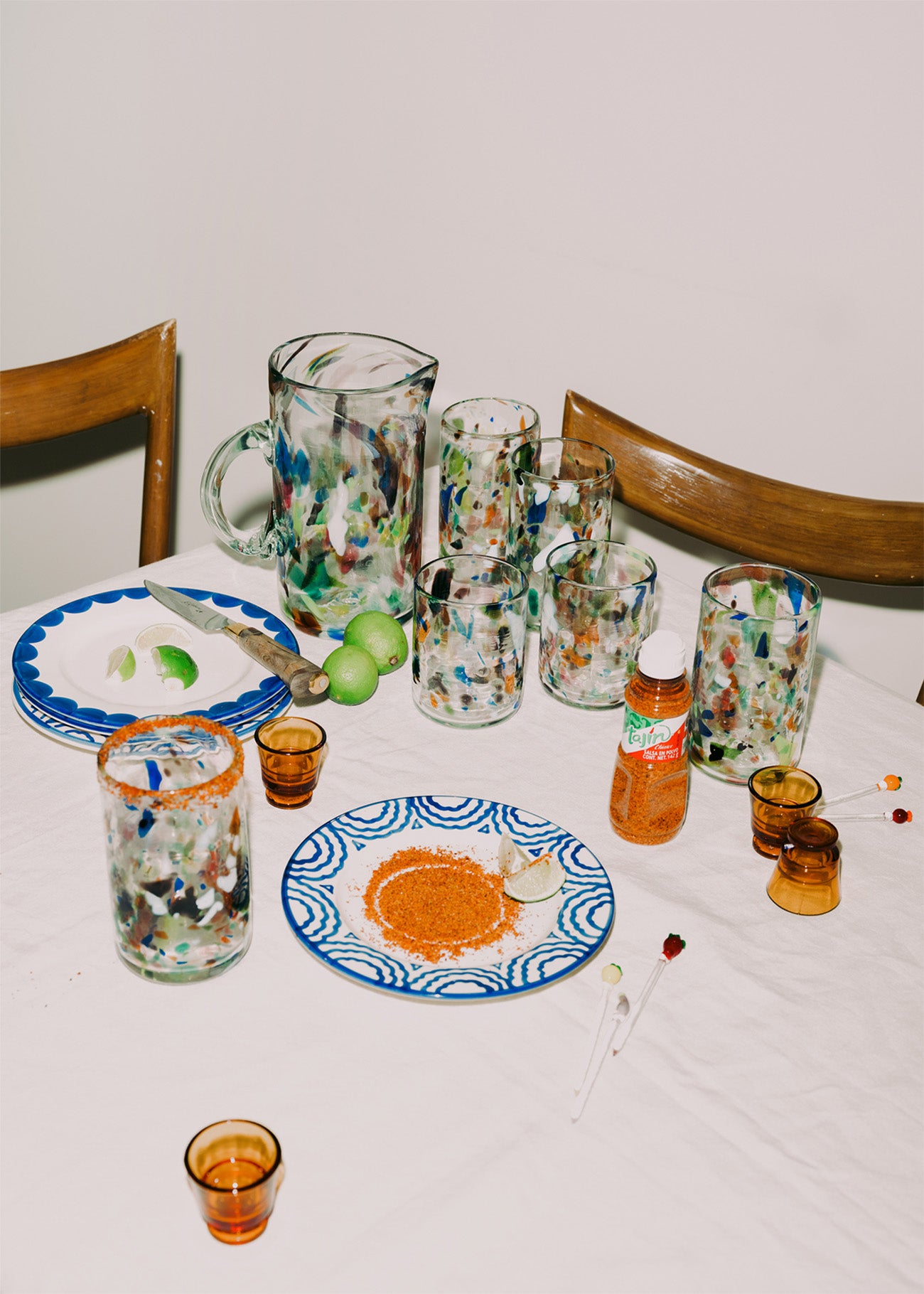 Table setting with colorful glassware and plates on a white tablecloth.
