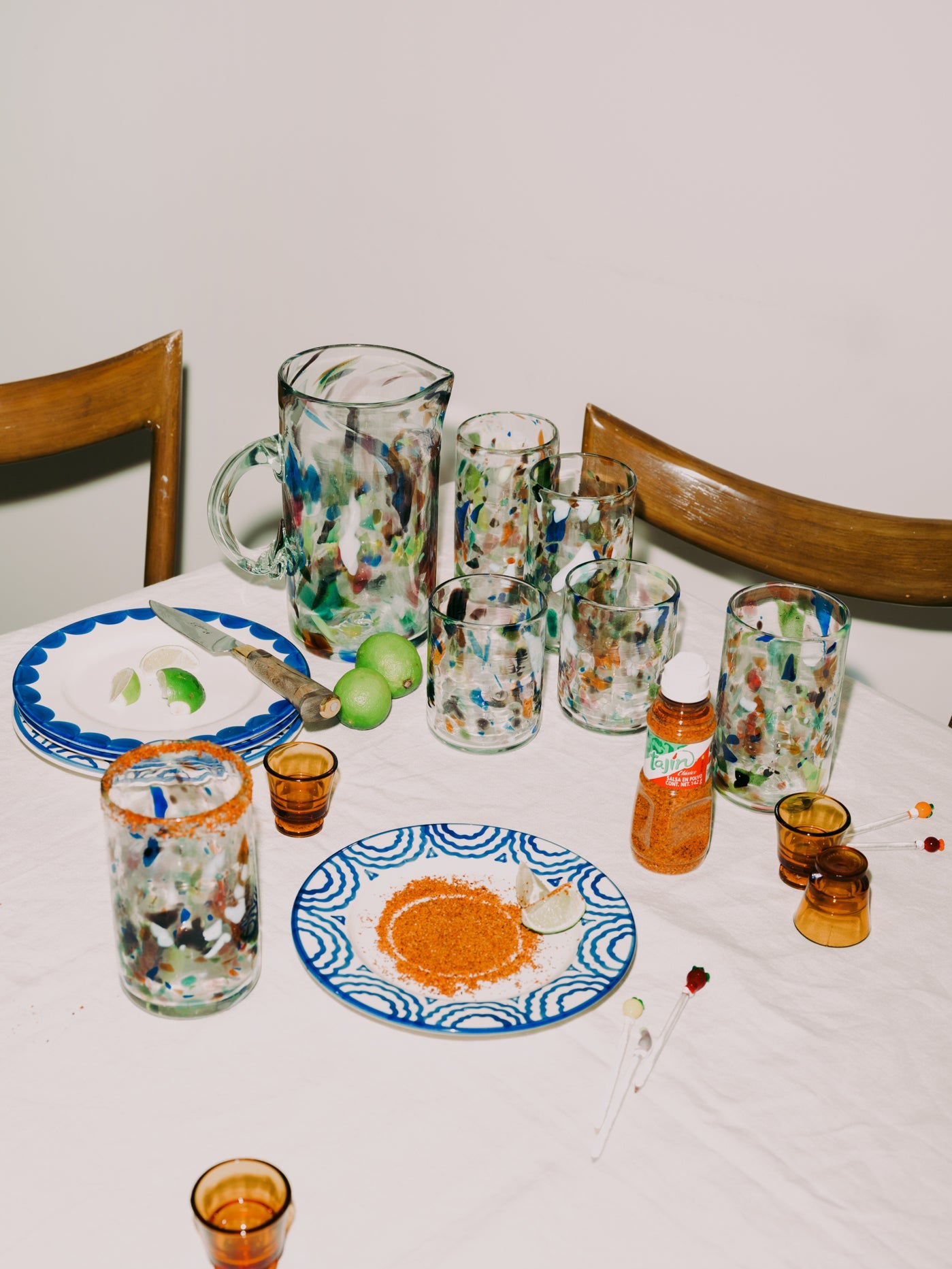 Dining table with glassware, plates, and bottles on a white tablecloth.