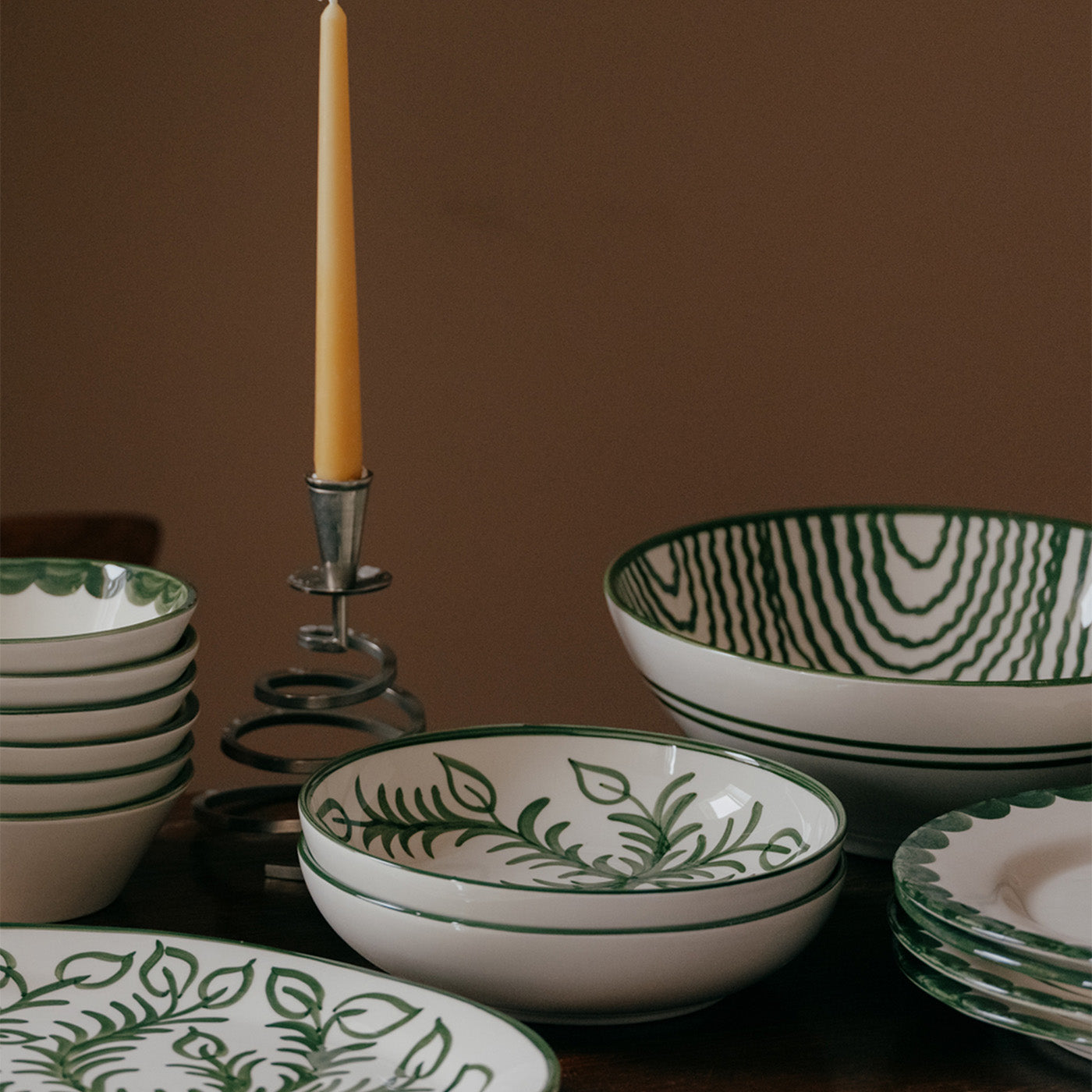 Ceramic bowls with green leaf patterns on a wooden surface against a brown background