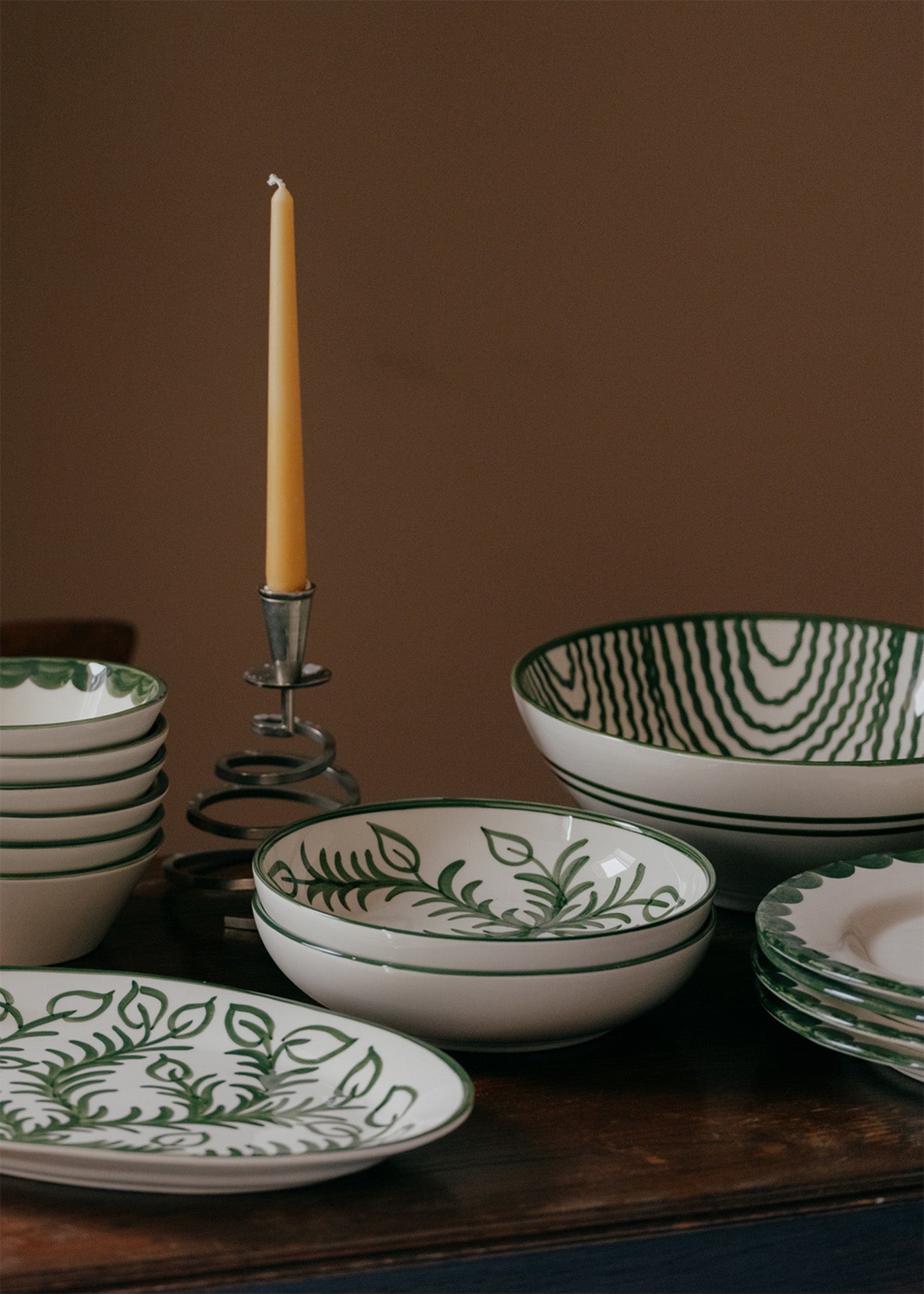 Ceramic bowls with green leaf patterns on a wooden surface against a brown background
